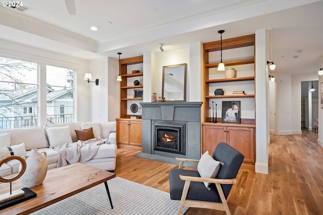 living area featuring a fireplace with flush hearth, baseboards, light wood-style floors, built in features, and ornamental molding