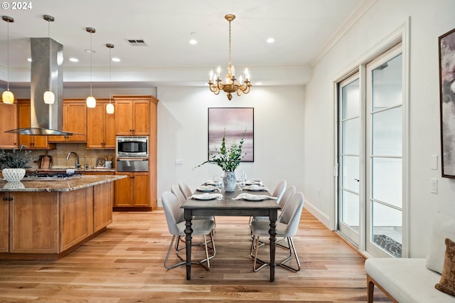 kitchen with visible vents, hanging light fixtures, dark stone counters, an island with sink, and island exhaust hood