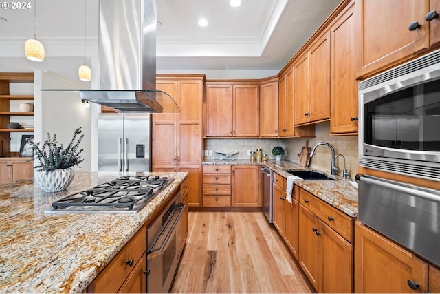 kitchen featuring light stone counters, decorative light fixtures, backsplash, light wood-style floors, and built in appliances