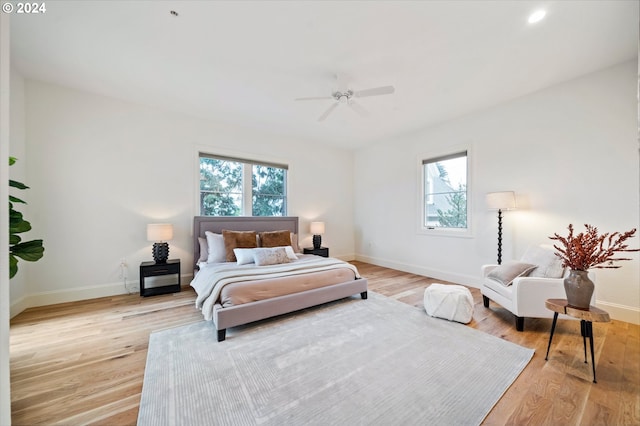 bedroom with light wood-style flooring, baseboards, and a ceiling fan