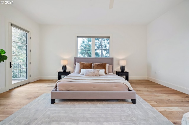 bedroom with access to outside, light wood finished floors, and baseboards