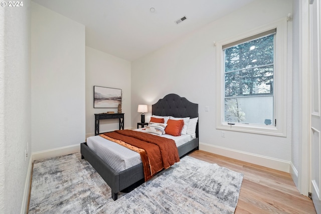 bedroom with baseboards, visible vents, and light wood finished floors