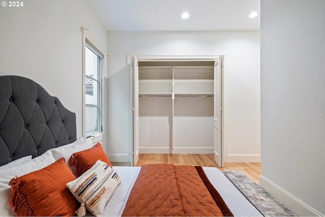 bedroom with light wood-type flooring, baseboards, a closet, and recessed lighting