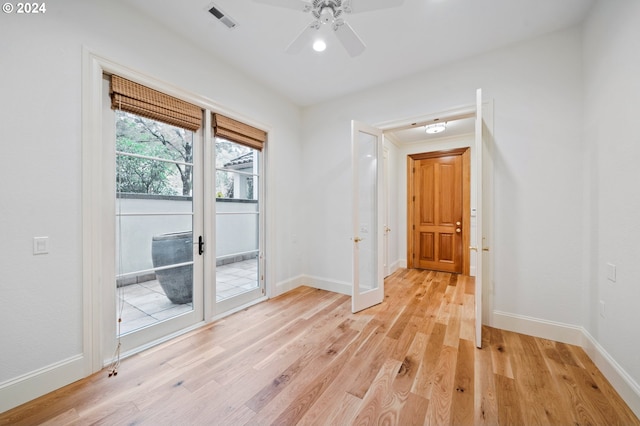 unfurnished room with a ceiling fan, light wood-type flooring, visible vents, and baseboards