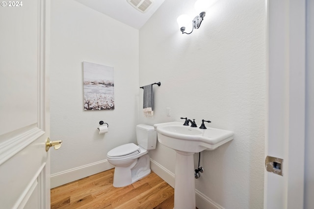 bathroom with baseboards, visible vents, toilet, and wood finished floors