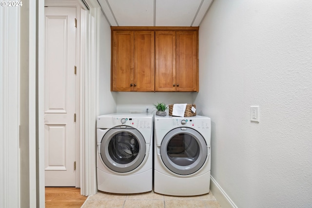 laundry room featuring cabinet space, baseboards, washer and clothes dryer, and light tile patterned flooring