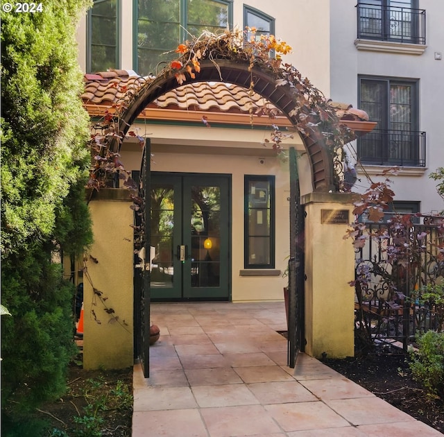 view of exterior entry with a patio area, french doors, a tile roof, and stucco siding