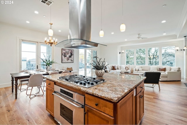 kitchen with open floor plan, hanging light fixtures, appliances with stainless steel finishes, and island exhaust hood