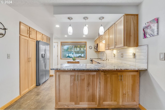 kitchen featuring sink, kitchen peninsula, light stone countertops, light brown cabinetry, and stainless steel fridge with ice dispenser