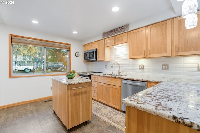 kitchen featuring sink, light stone counters, decorative backsplash, a kitchen island, and appliances with stainless steel finishes