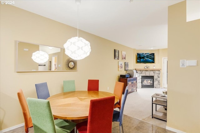 dining space with carpet and a stone fireplace