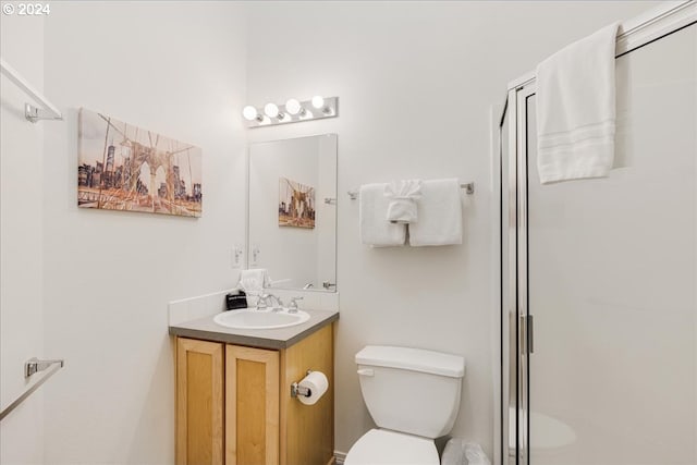 bathroom with vanity, toilet, and a shower with shower door