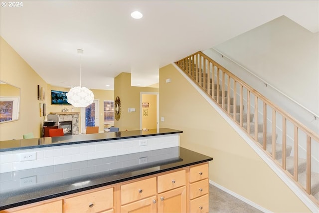 kitchen with light brown cabinets and a stone fireplace