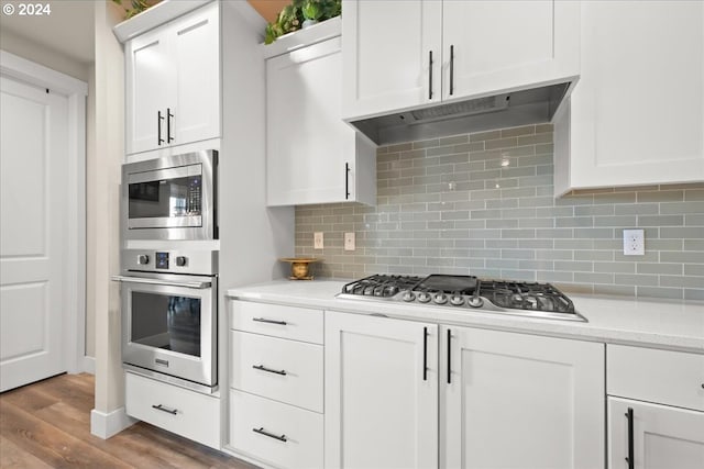 kitchen featuring hardwood / wood-style flooring, stainless steel appliances, tasteful backsplash, and white cabinets