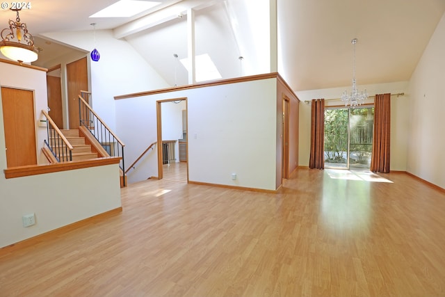 unfurnished living room featuring a skylight, light wood-type flooring, beamed ceiling, high vaulted ceiling, and an inviting chandelier