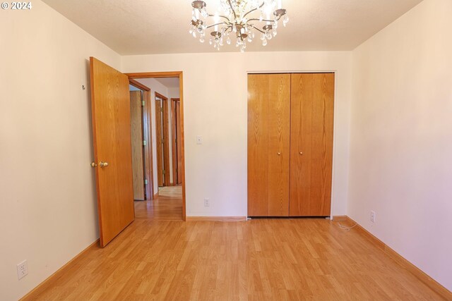 3794 Wilshire Ln, Eugene, OR 97405 - unfurnished bedroom with light wood-style flooring, a chandelier, a closet, and baseboards