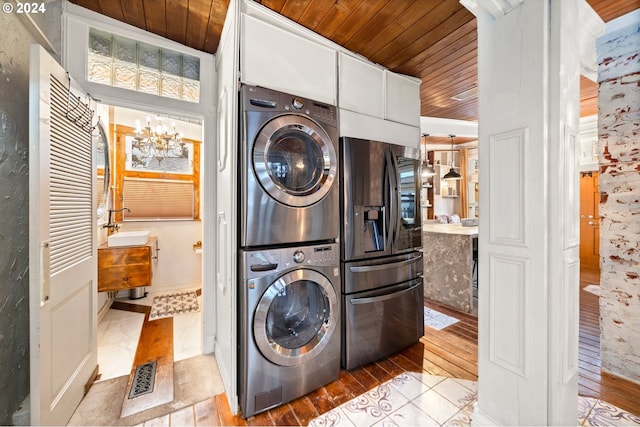 laundry area with wooden ceiling, stacked washing maching and dryer, and light hardwood / wood-style floors