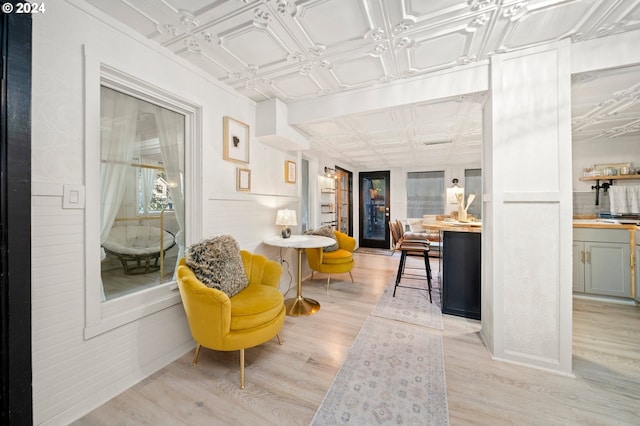 living area with coffered ceiling and light wood-type flooring