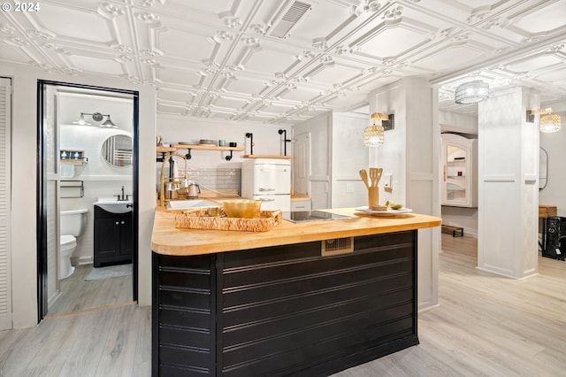 bar featuring coffered ceiling, cooktop, sink, light hardwood / wood-style flooring, and butcher block countertops