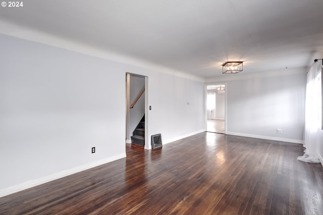 empty room featuring dark hardwood / wood-style floors, a chandelier, and plenty of natural light