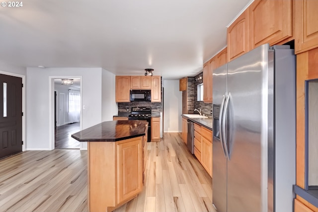 kitchen with backsplash, black appliances, light wood-type flooring, and light brown cabinets