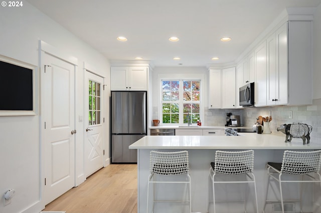 kitchen with a wealth of natural light, white cabinets, kitchen peninsula, and stainless steel appliances