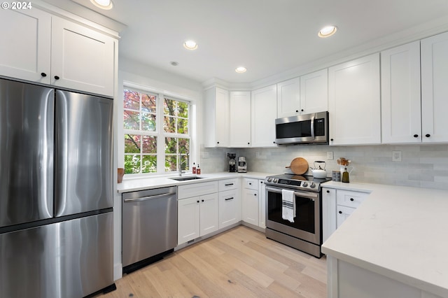 kitchen with backsplash, stainless steel appliances, light wood-type flooring, and white cabinets