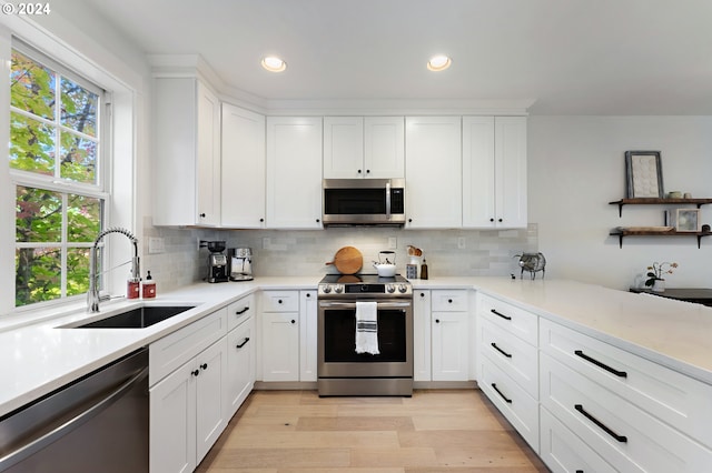 kitchen featuring tasteful backsplash, appliances with stainless steel finishes, sink, light wood-type flooring, and white cabinets