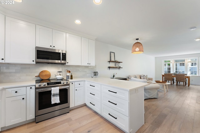 kitchen featuring decorative light fixtures, kitchen peninsula, stainless steel appliances, and white cabinetry