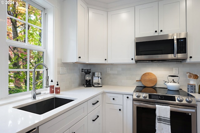 kitchen with white cabinetry, appliances with stainless steel finishes, sink, and decorative backsplash