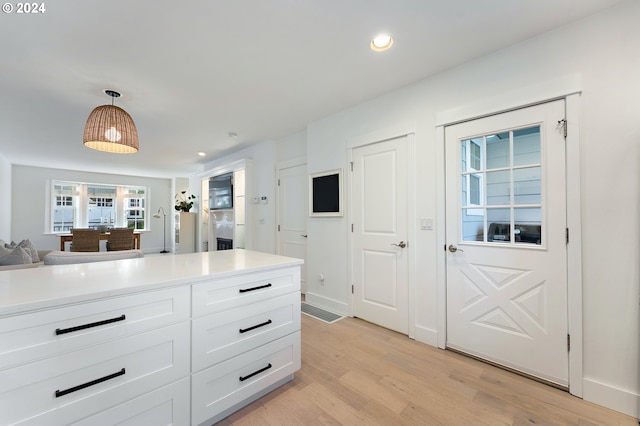 kitchen featuring white cabinetry, light hardwood / wood-style flooring, and decorative light fixtures