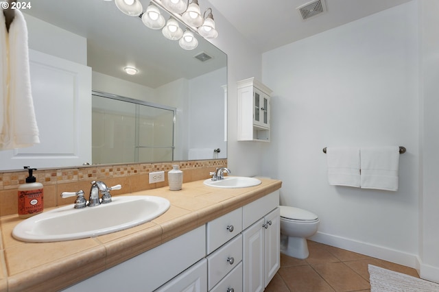 bathroom with toilet, tile patterned floors, walk in shower, vanity, and decorative backsplash