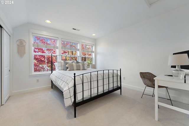 bedroom featuring lofted ceiling, light colored carpet, and a closet