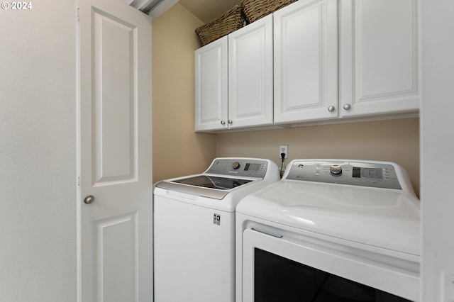 clothes washing area with cabinets and washer and clothes dryer