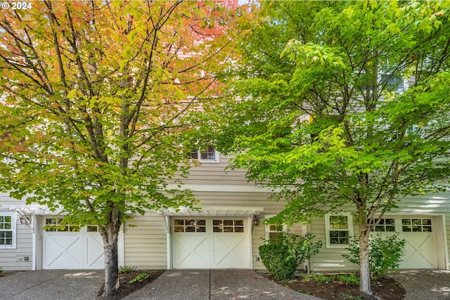 view of property hidden behind natural elements featuring a garage