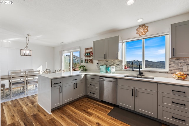 kitchen with kitchen peninsula, dark hardwood / wood-style flooring, gray cabinetry, sink, and dishwasher