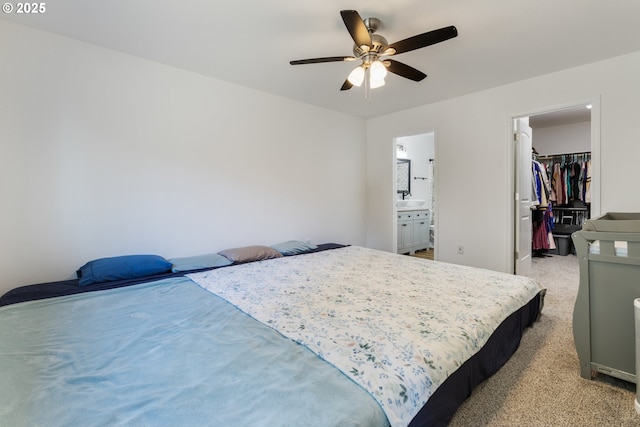 bedroom with light carpet, a walk in closet, ensuite bath, ceiling fan, and a closet