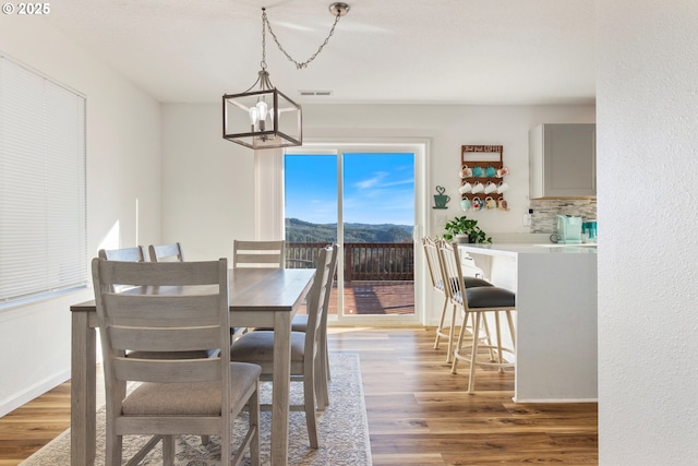 dining space with a mountain view, dark hardwood / wood-style floors, and an inviting chandelier