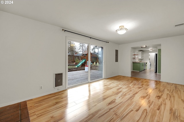 unfurnished room with electric panel and light hardwood / wood-style floors