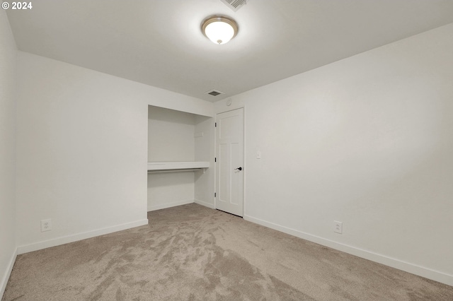 unfurnished bedroom featuring light colored carpet and a closet