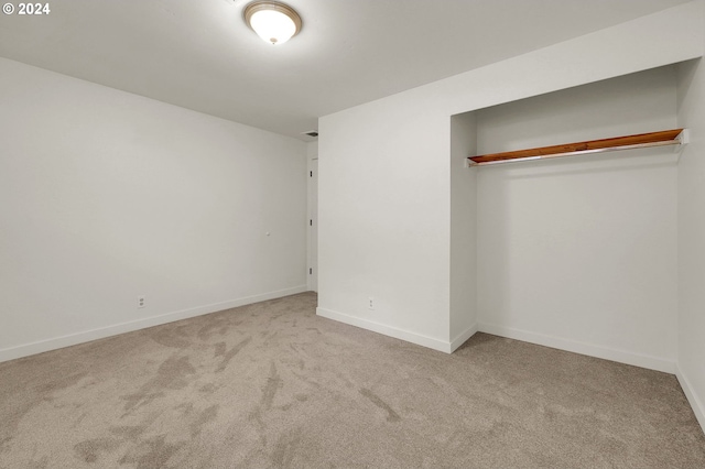 unfurnished bedroom with light carpet and a closet