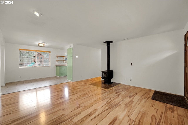 unfurnished living room featuring light wood-type flooring and a wood stove