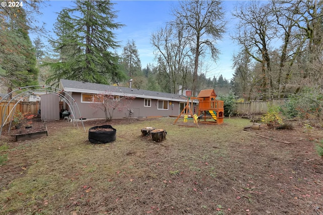 rear view of property with a playground and an outdoor fire pit