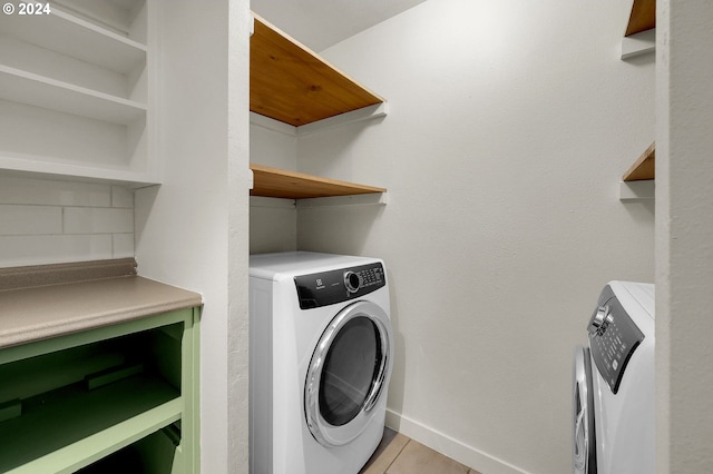 clothes washing area featuring light tile patterned floors and washer and dryer