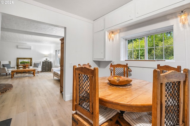 dining space with light hardwood / wood-style flooring and an AC wall unit