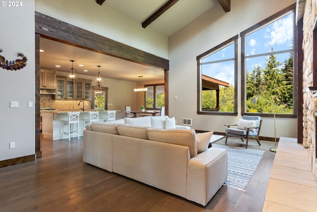 living room with beamed ceiling, sink, dark wood-type flooring, and an inviting chandelier