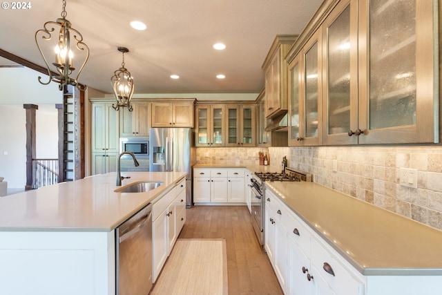 kitchen with stainless steel appliances, hanging light fixtures, a spacious island, and sink