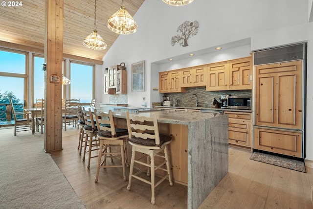 79274 Ray Brown Rd, Arch Cape, OR 97102 - kitchen with decorative backsplash, light wood-type flooring, paneled refrigerator, a chandelier, and a kitchen island