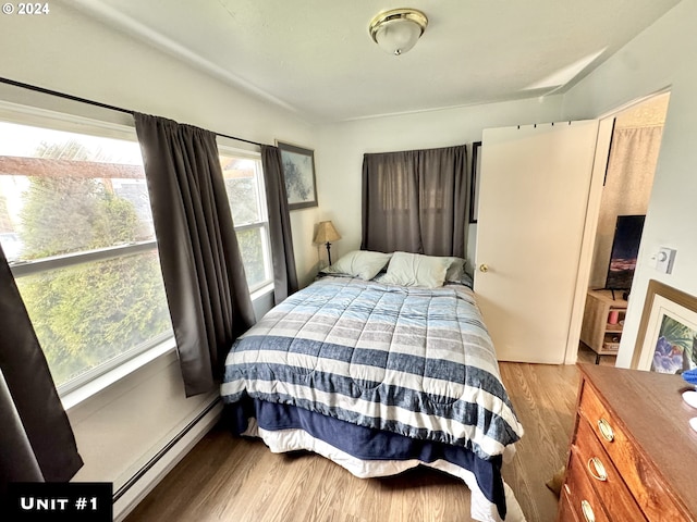 bedroom with baseboard heating and wood-type flooring