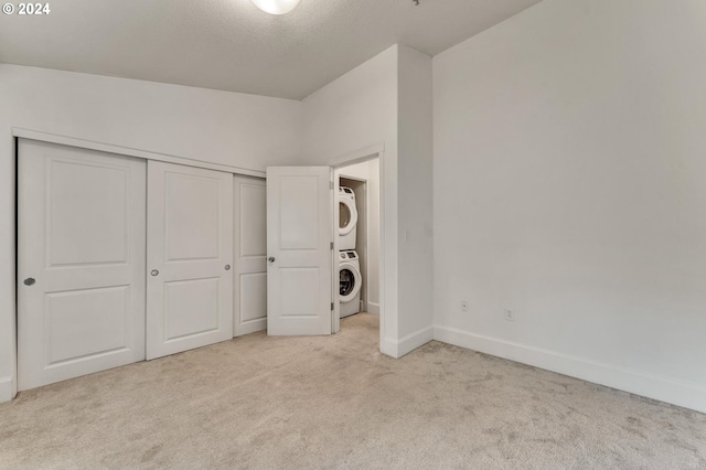 unfurnished bedroom featuring a closet, stacked washing maching and dryer, and light carpet